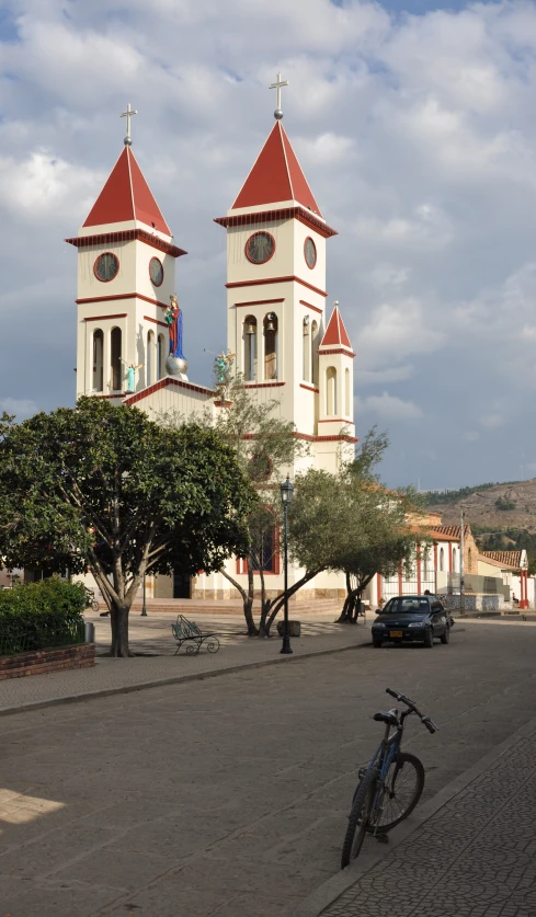 a bicycle parked next to a church building on a dirt road