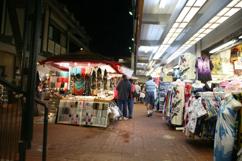 a storefront with people in front and many selling merchandise on the sidewalk