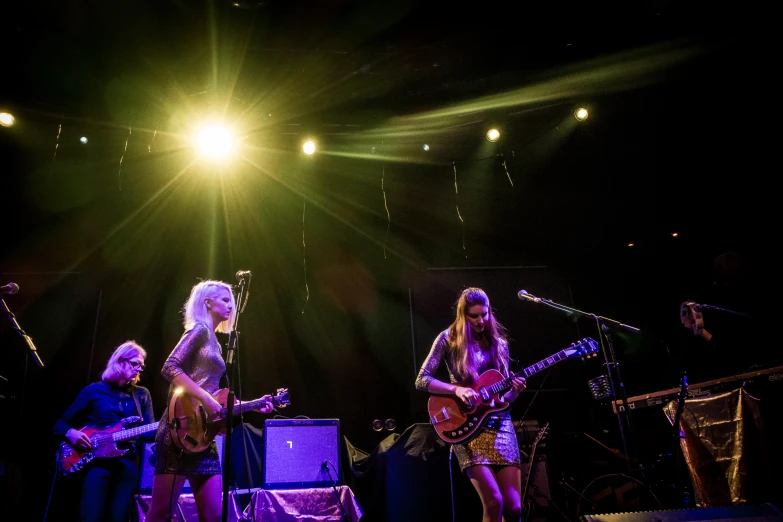 three women on stage with guitars and microphones