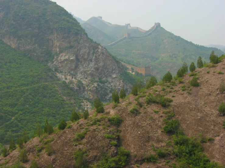 a rocky landscape with green trees and mountains in the background