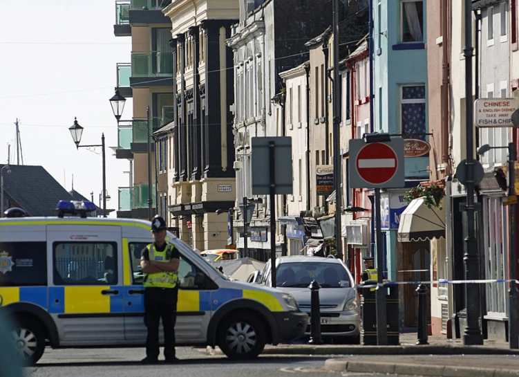 police officer standing by car next to city street