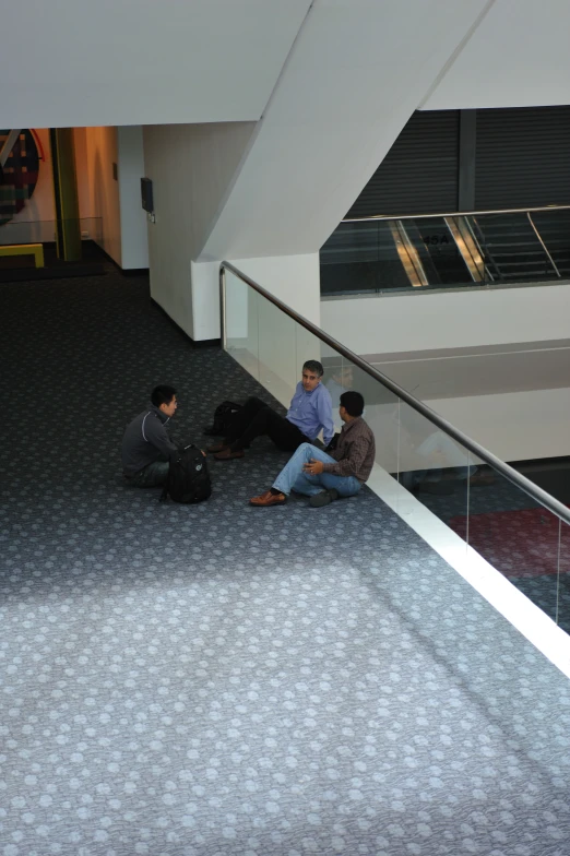 three men sitting on the ground talking and waiting