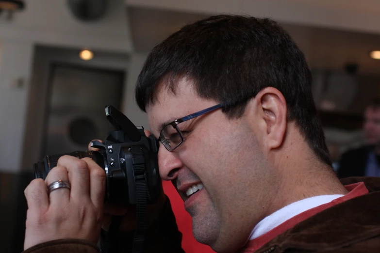 man with glasses taking picture through a camera