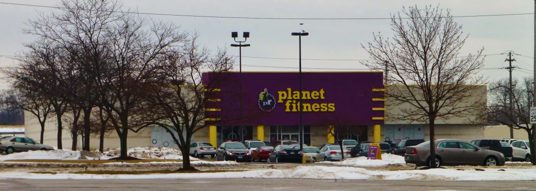 a planet fitness store and parking lot, in the winter