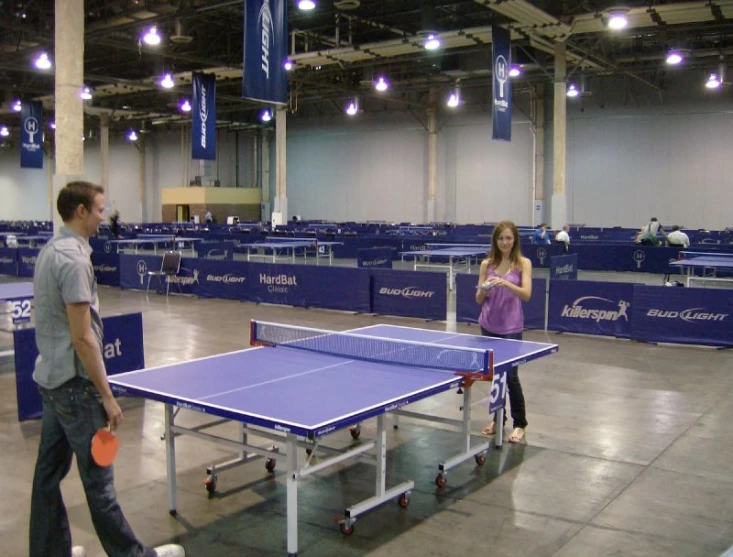 a couple is playing ping pong at the indoor court