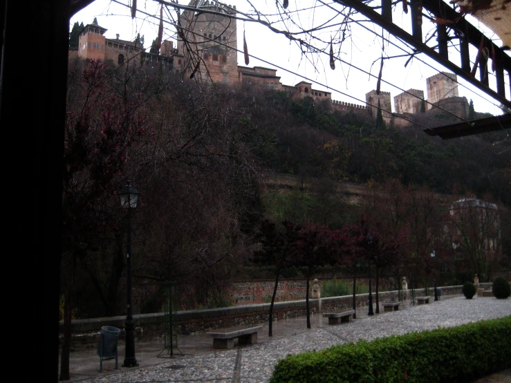 a building with trees on the hillside is seen from a rainy day