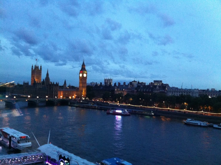 boats floating in the river near a bridge with big ben in the distance