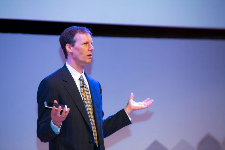 a man in a suit standing on a stage talking