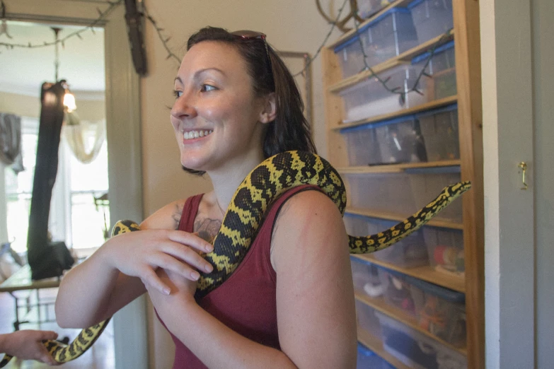 a young lady smiles and holds her pet snake in a store