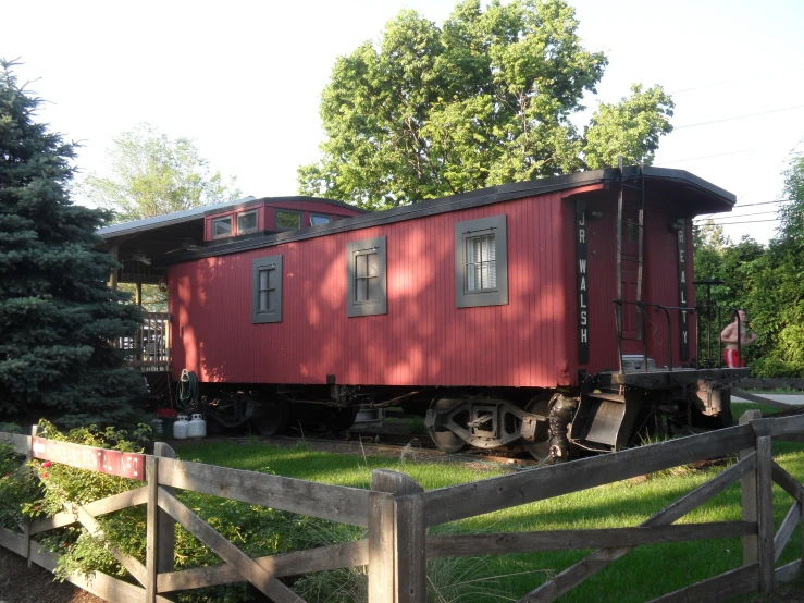 an old - fashioned train caboose sitting on grass behind a fence