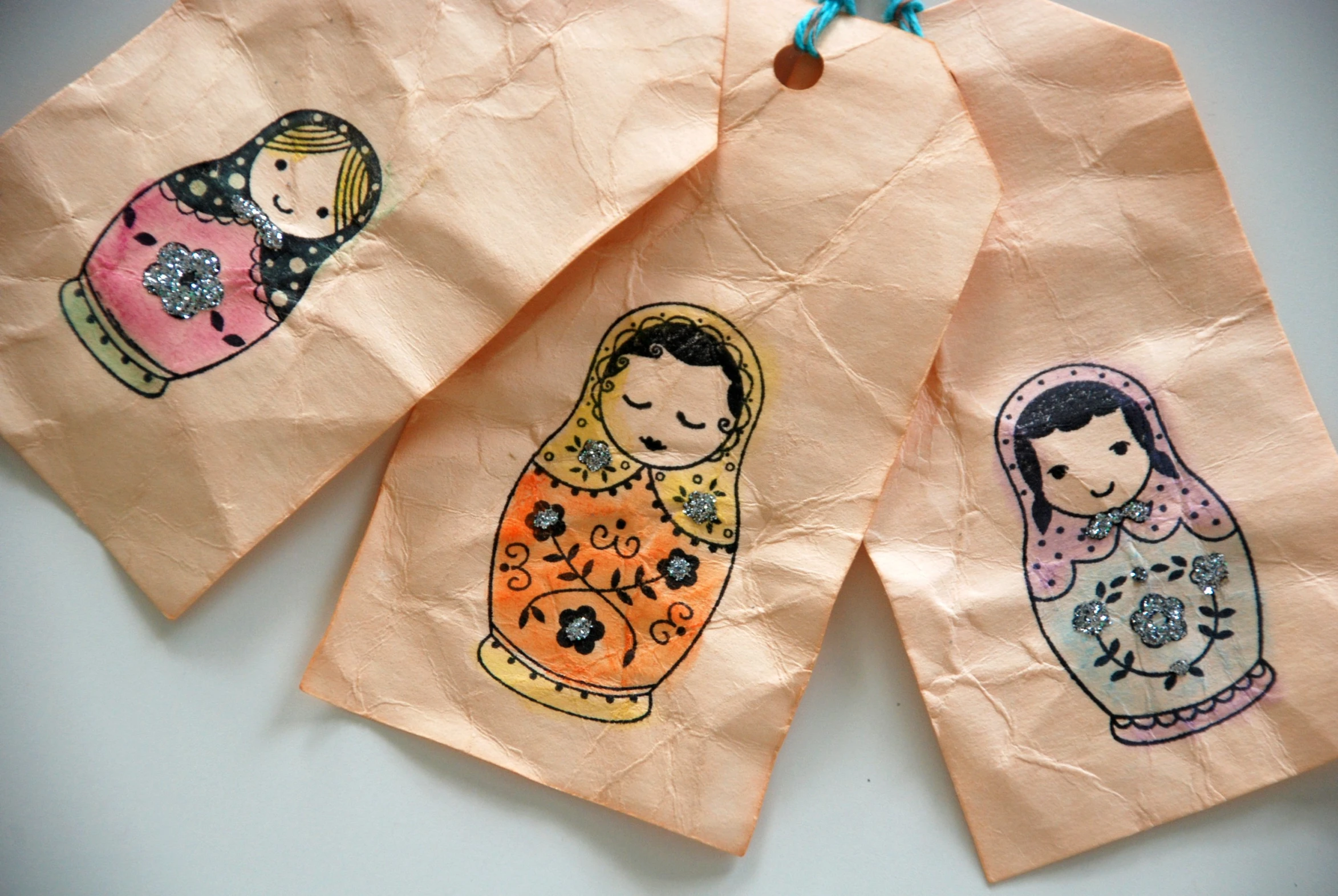 three handmade paper bags with pictures of matry dolls on them