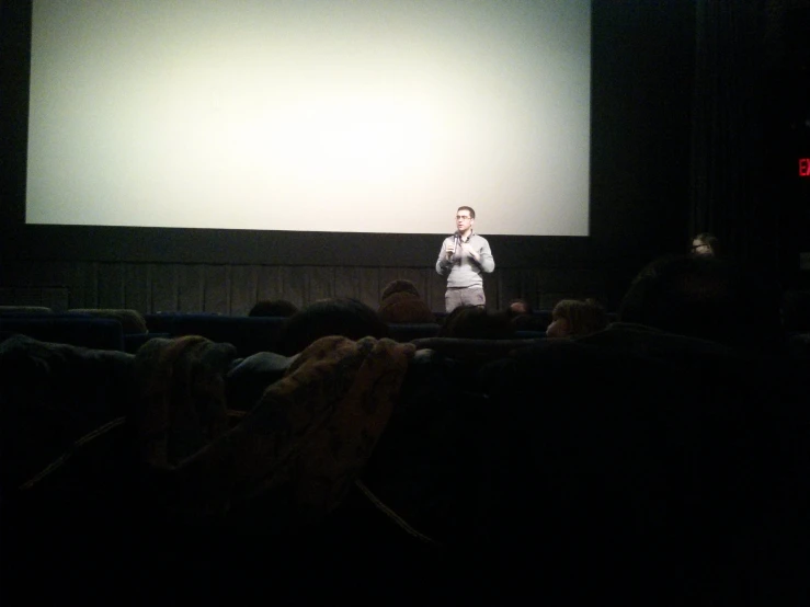 a man holding a smart phone while standing in front of an audience