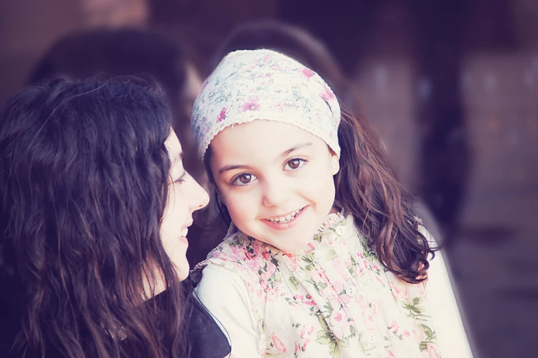 a smiling little girl sitting next to her mother