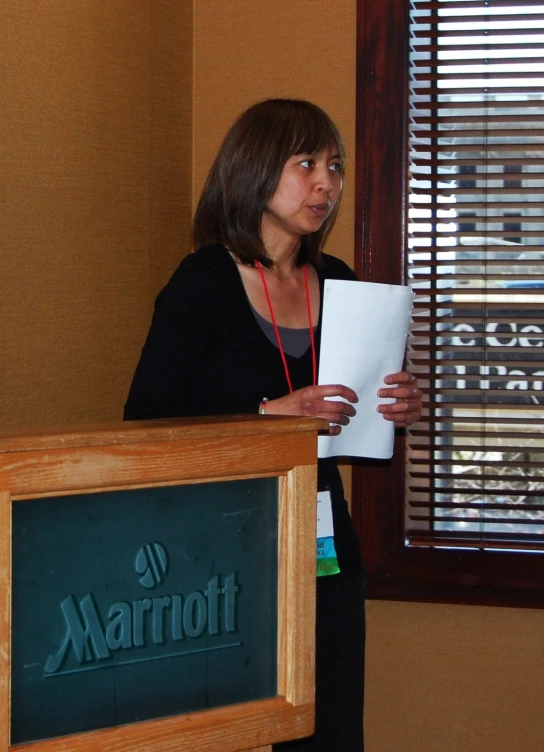 a woman standing in front of a microphone with a paper