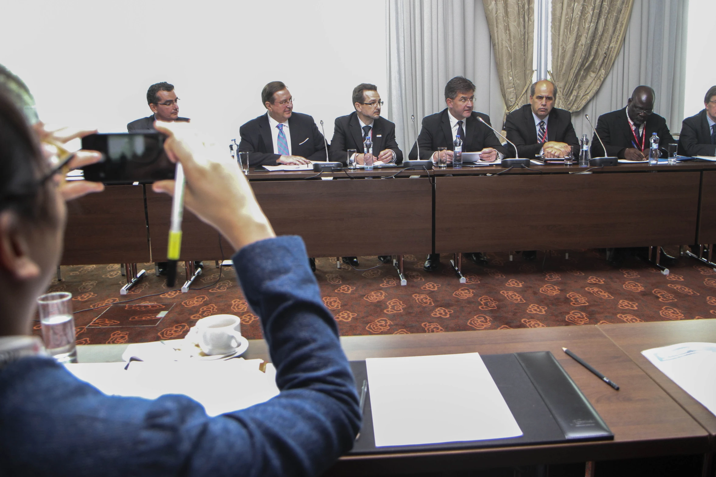 a group of men in business suits sit at the front of a conference room while someone takes a po