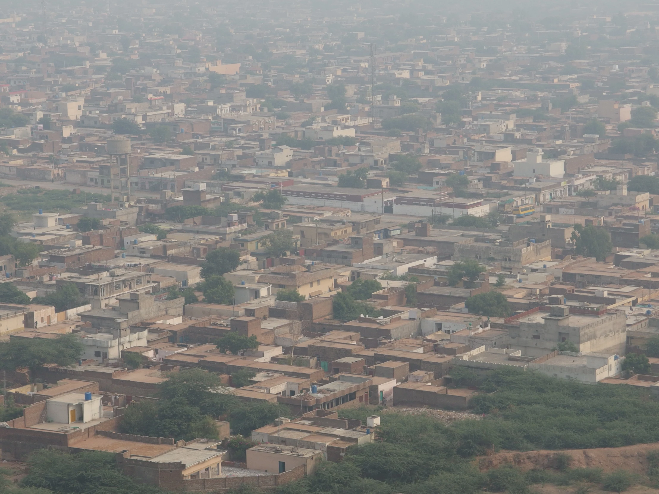 a city with trees, buildings and brown dirt roads