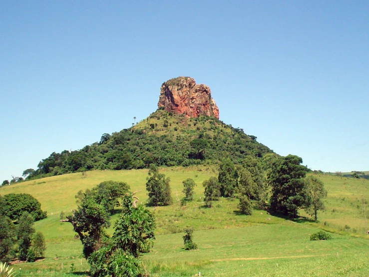 an image of a very large mountain surrounded by green fields