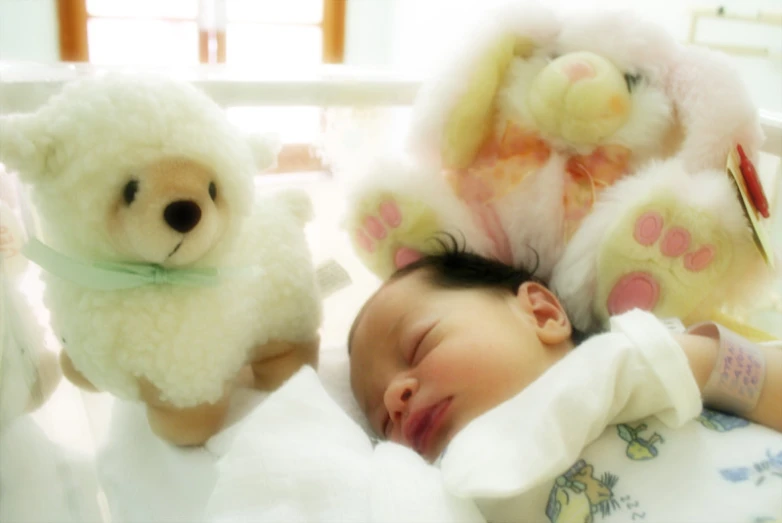 a baby laying in a bed with stuffed animals