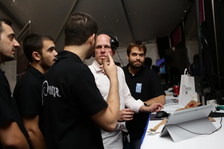 a group of men standing in front of a computer screen