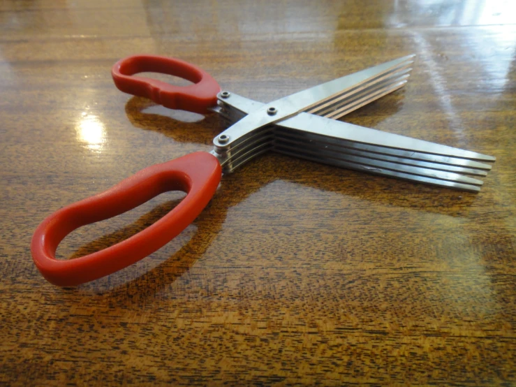 pair of red scissors on top of a wooden table