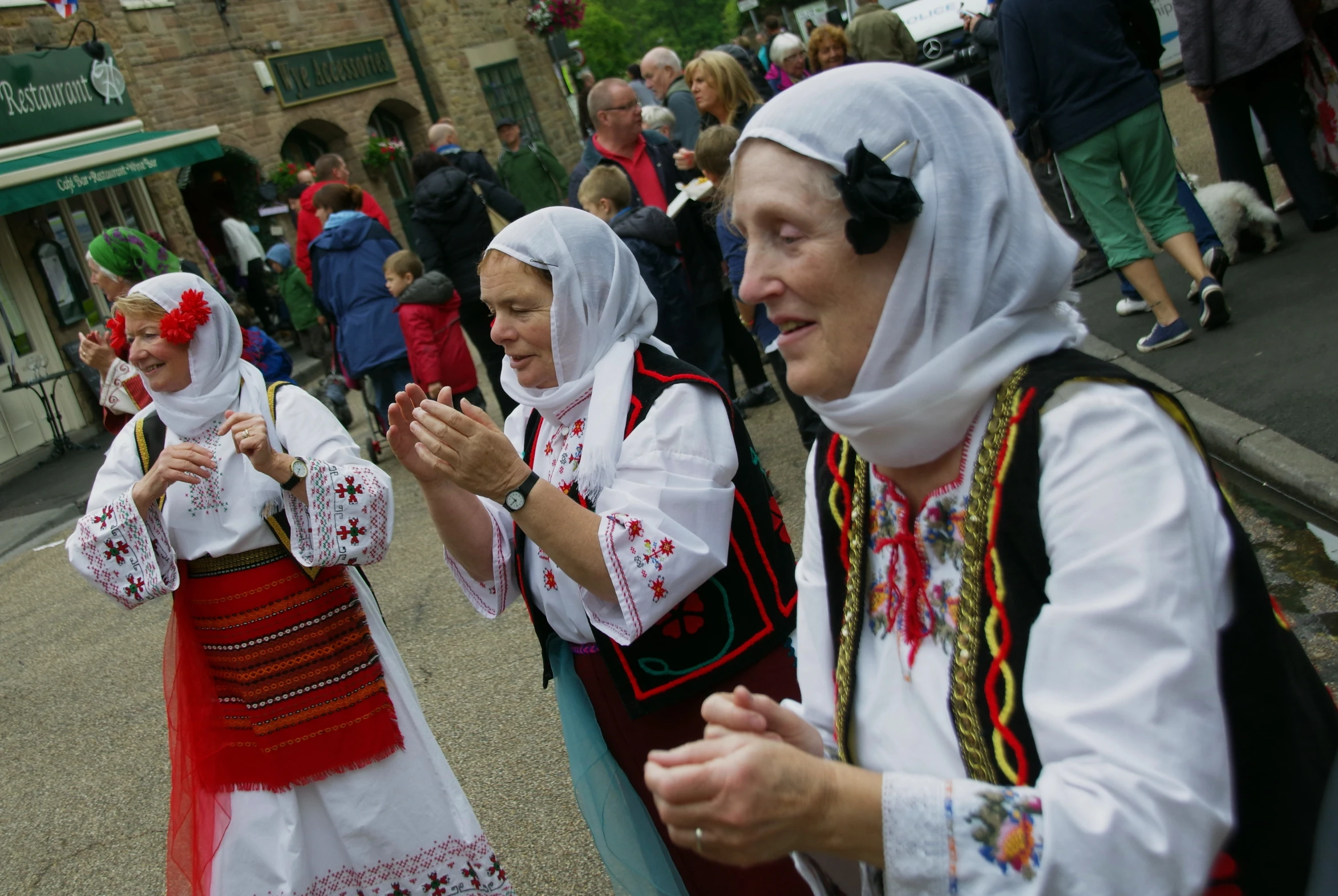 several people in traditional clothes dancing and talking on the street