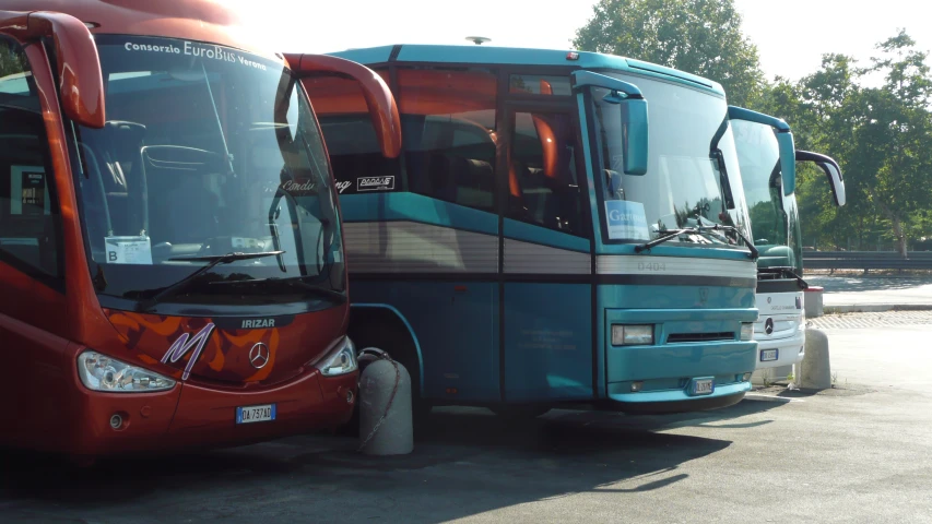 two blue and red buses are parked in a lot
