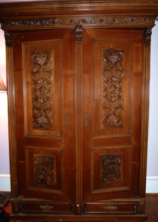 a wood wardrobe sitting in a bedroom next to a lamp