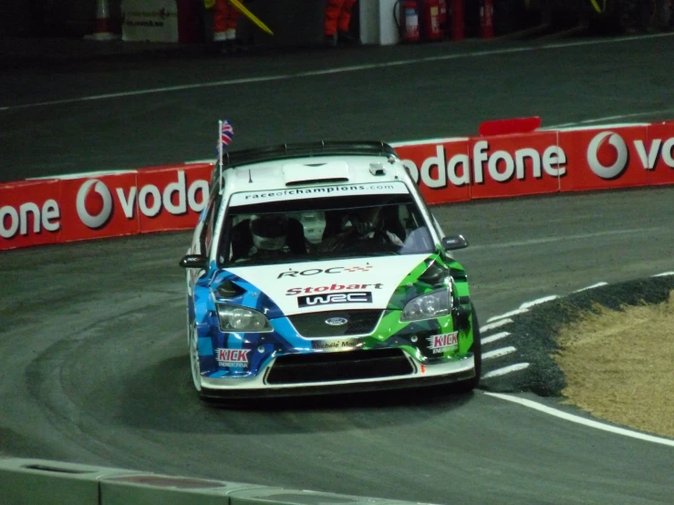 a rally car with green and blue paint driving on a race track