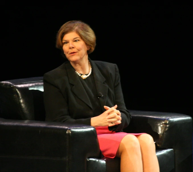 a woman sitting in a black chair with her legs crossed