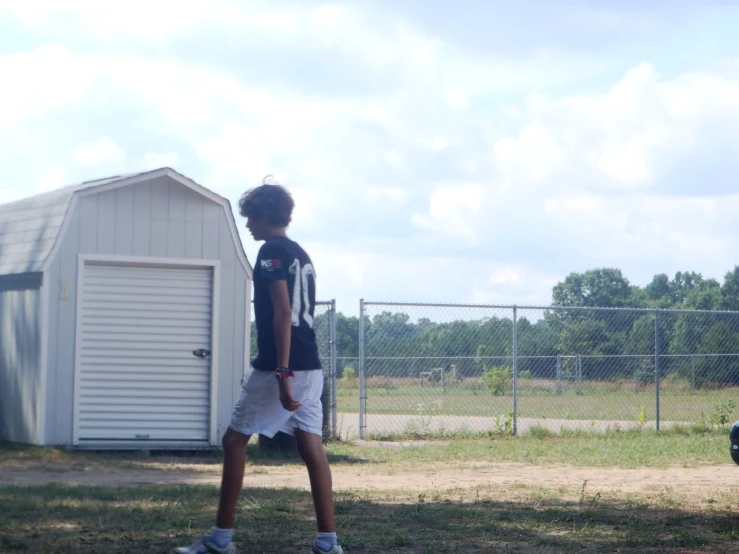 a boy in a baseball uniform is standing by a fence