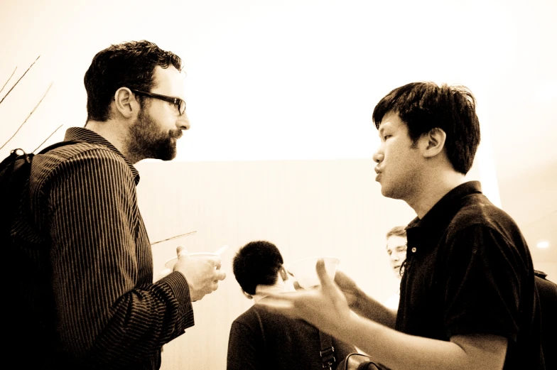 two men stand together drinking wine together