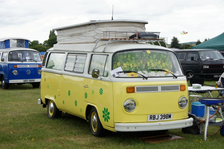 an old vw bus sitting in the grass at a car show