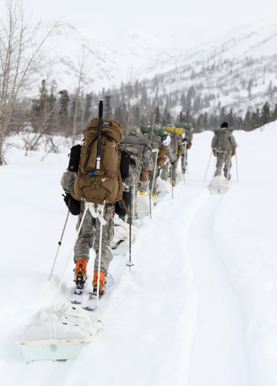 several soldiers walking on skis across a snow covered hill