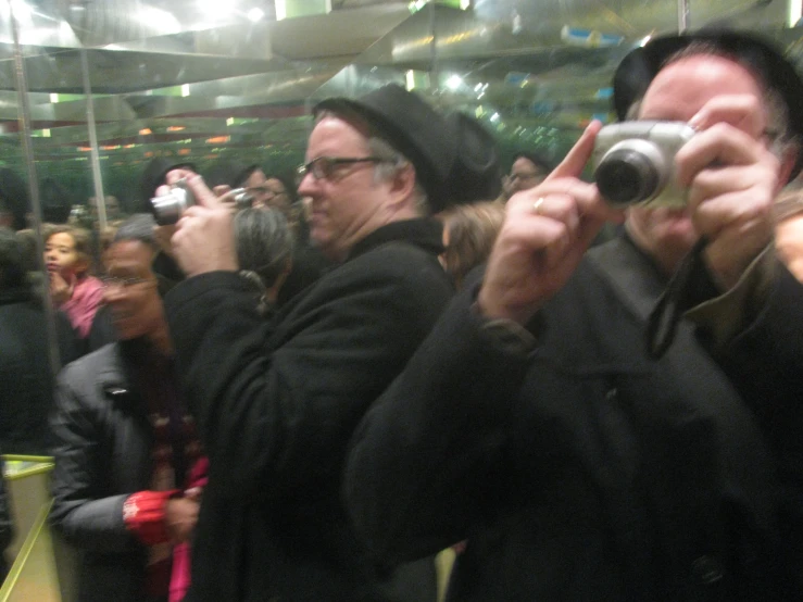 a group of people taking pos of themselves with cameras