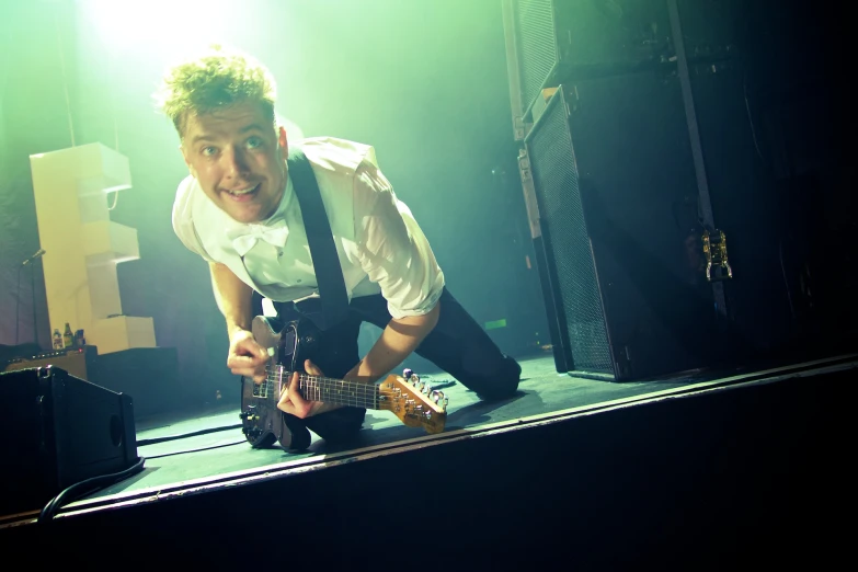 a young man holding an electric guitar on stage