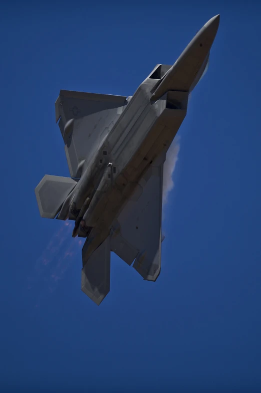 a military jet flying through a blue sky