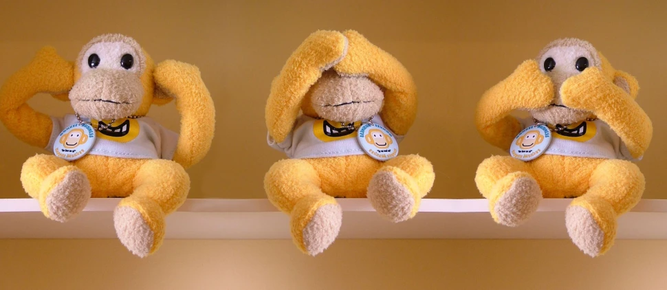 a shelf with three stuffed animal hanging above