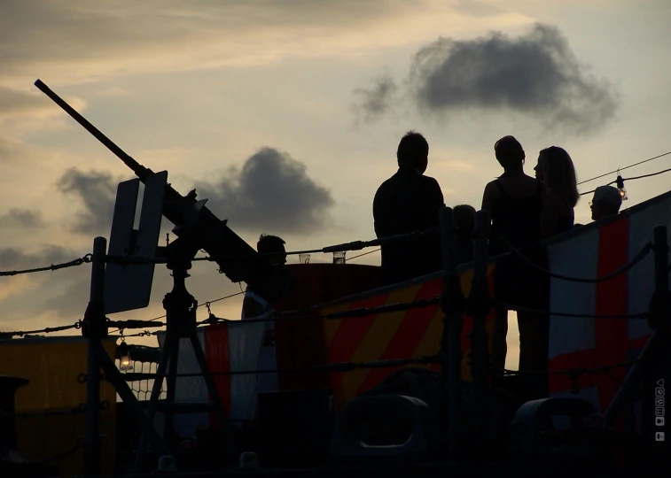 three people sit on a boat and watch the sun set