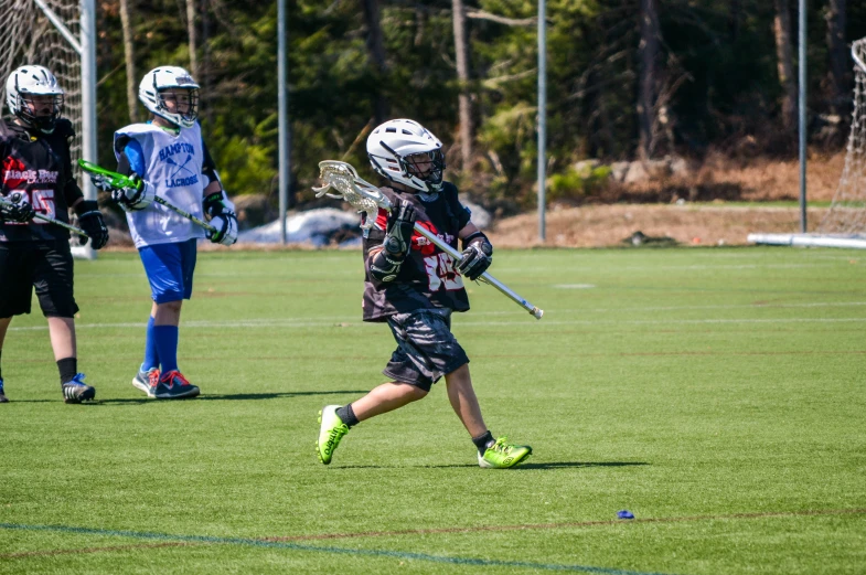 a little  wearing lacrosse gear runs with the ball