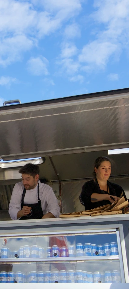 two people standing next to each other looking out from a restaurant