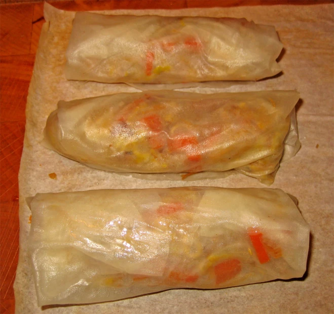 two homemade rolls made of dumplings sit on a piece of parchment paper