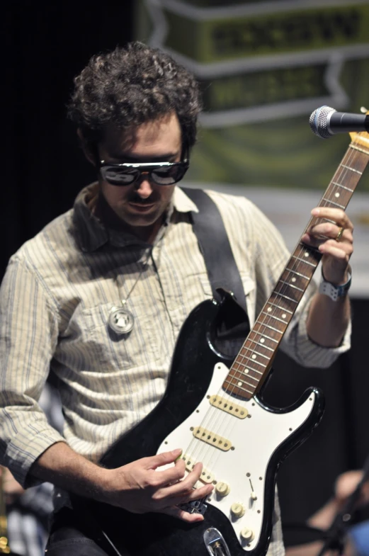 a man holding an electric guitar and wearing sunglasses