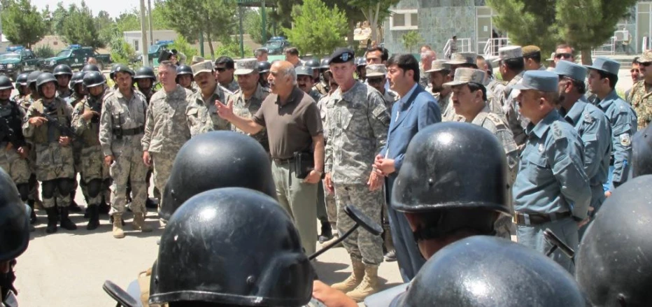 several men standing in front of military helmets talking to someone else
