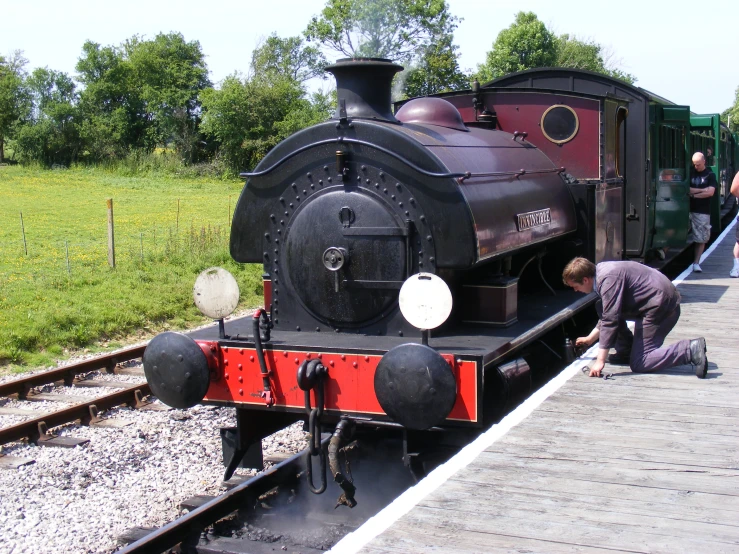 an old locomotive is at a train station with people around