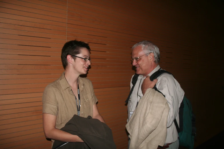 two men talking next to a wall together