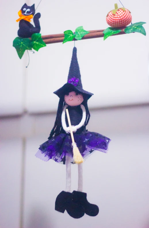 an adorable little witch hanging from a tree nch