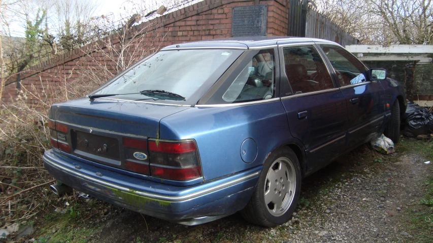 an older blue car parked near an old brick house