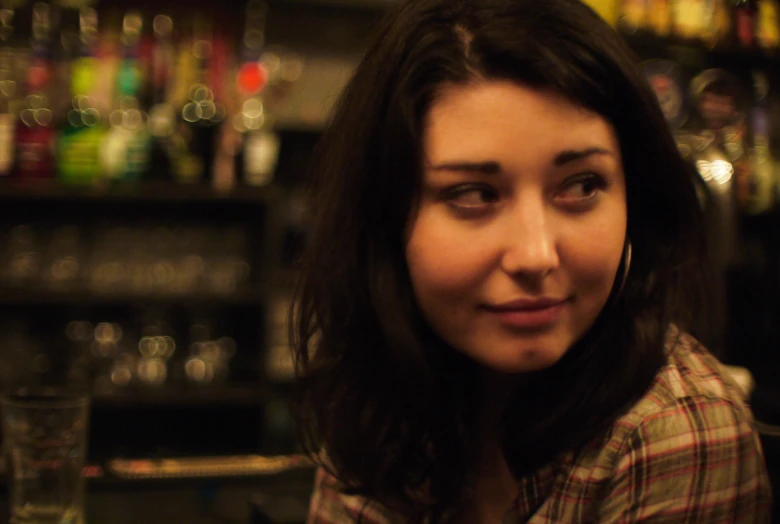 a woman standing in front of a bar full of alcohol