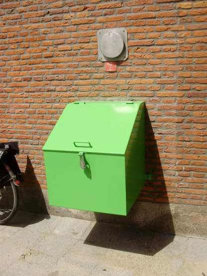 a very big bright green box by a brick wall
