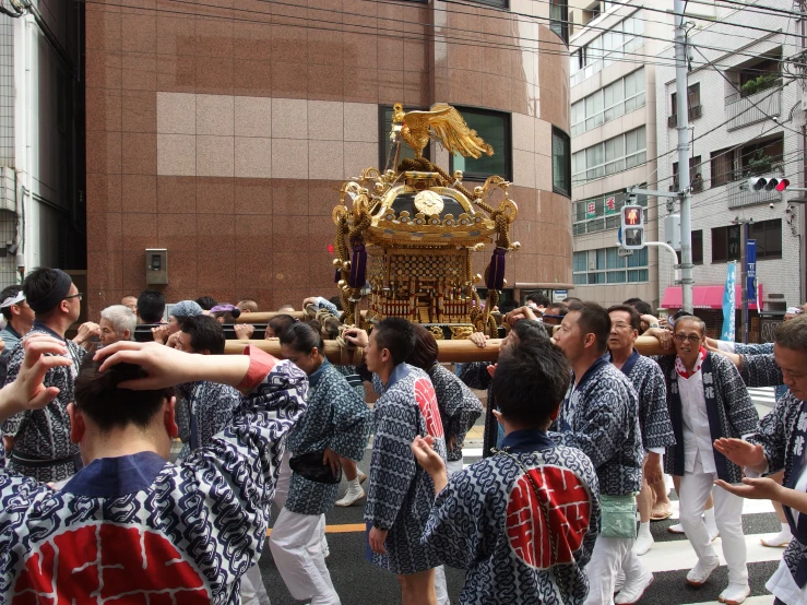 men in kimonos dancing around a large golden statue